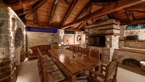 A rustic stone fireplace, wooden dining table, and chairs in a cozy interior. - Villa Kos (Murter-Kornati)