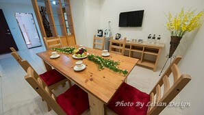 A dining area with a wooden table, red cushioned chairs, a fruit centerpiece, and a small bench with bottles. - Beautiful Mansion B&B (Wujie)