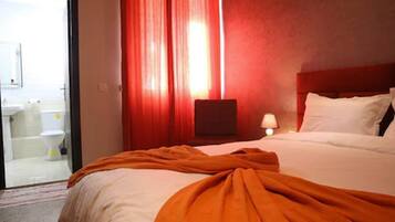 Une chambre d’hôtel avec un lit, une table de chevet, une lampe et vue sur la salle de bain.
