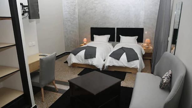 Een hotelkamer met twee bedden, een bank, een eettafeltje en een televisie.
