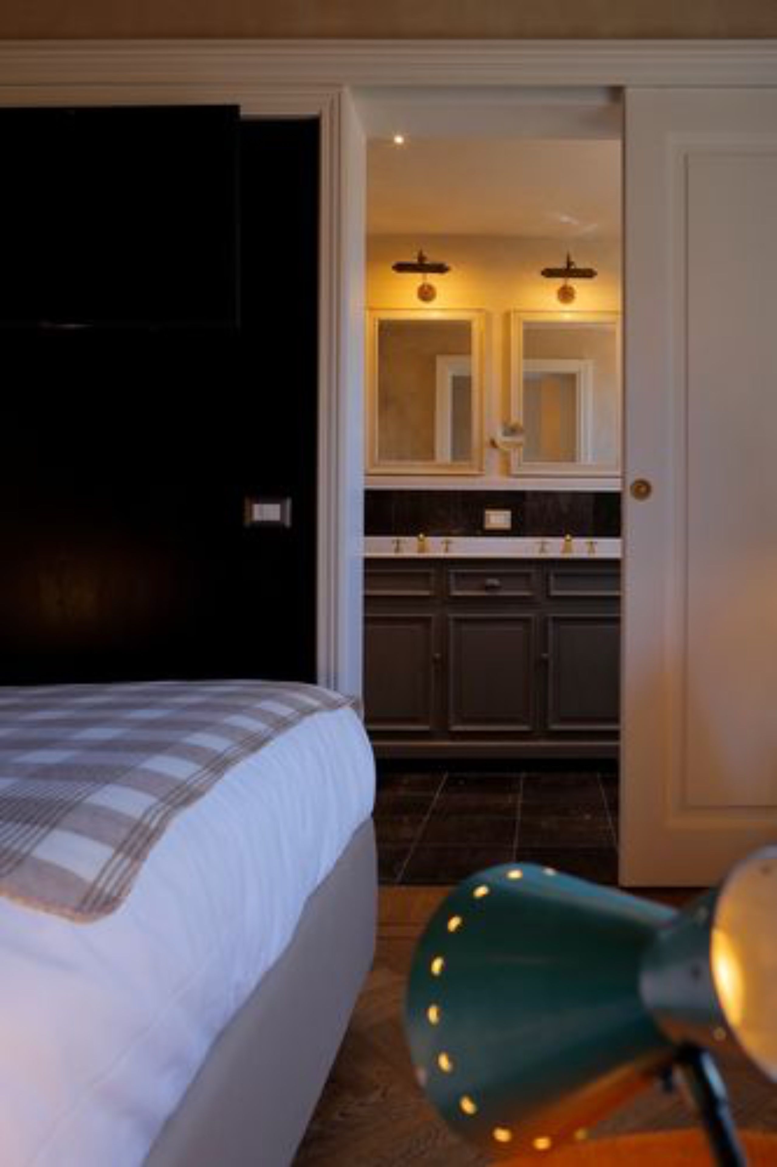 A bedroom with a bed, a nightstand, and a green lamp.