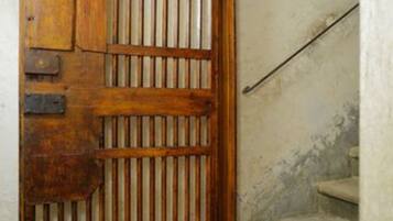 A wooden gate with vertical bars, a brick floor, and a staircase with a handrail.