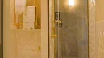A bathroom with a glass-enclosed shower, a toilet, and a towel rack with a towel.
