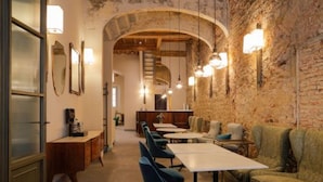A restaurant with a rustic interior, featuring exposed brick walls, wooden beams, and a long counter with blue upholstered chairs. - Residenza La Musa Amarcord (Florence)