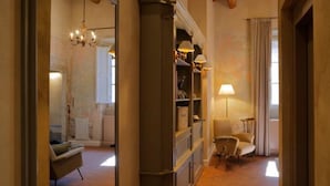 A hallway with a chandelier, a bookshelf, and a lamp. - Residenza La Musa Amarcord (Florence)