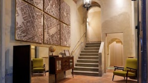 A lobby with a staircase, a reception desk, and two green armchairs. - Residenza La Musa Amarcord (Florence)