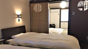 Une chambre d’hôtel avec deux lits, une cloison en bois et une vue sur une autre chambre.