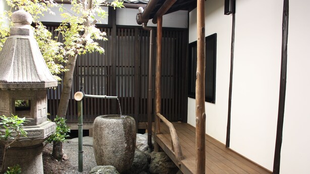 Un jardin japonais traditionnel agrémenté d’une lanterne en pierre, d’un pont en bois et d’une clôture en bambou.