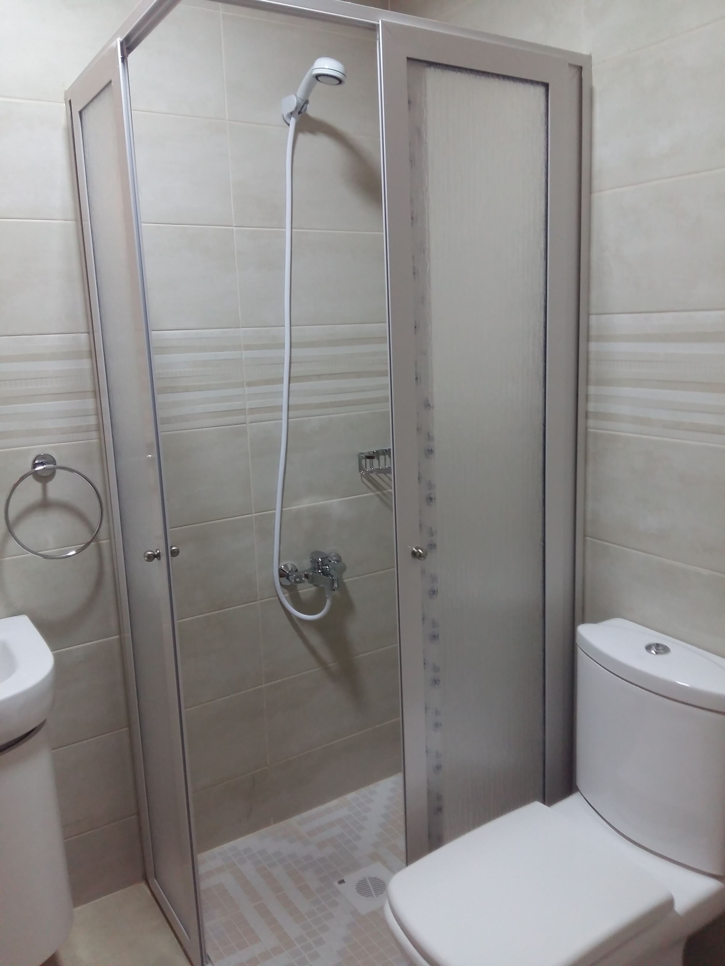 A bathroom with a glass-enclosed shower, a toilet, and a sink.