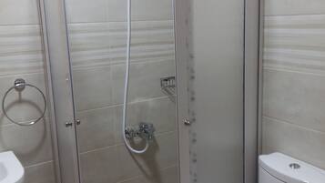 A bathroom with a glass-enclosed shower, a toilet, and a sink.