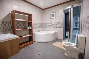 Een moderne badkamer met bad, toilet en een douche met glazen wanden.