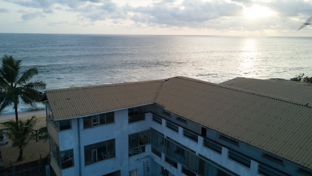 Un edificio a più piani con tetto piatto, affacciato su una spiaggia e l'oceano.