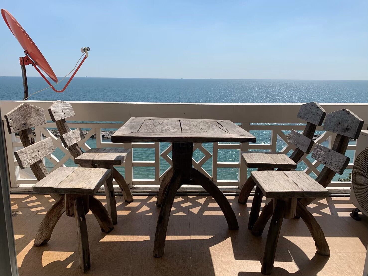 A wooden deck with a table and chairs, overlooking a body of water.