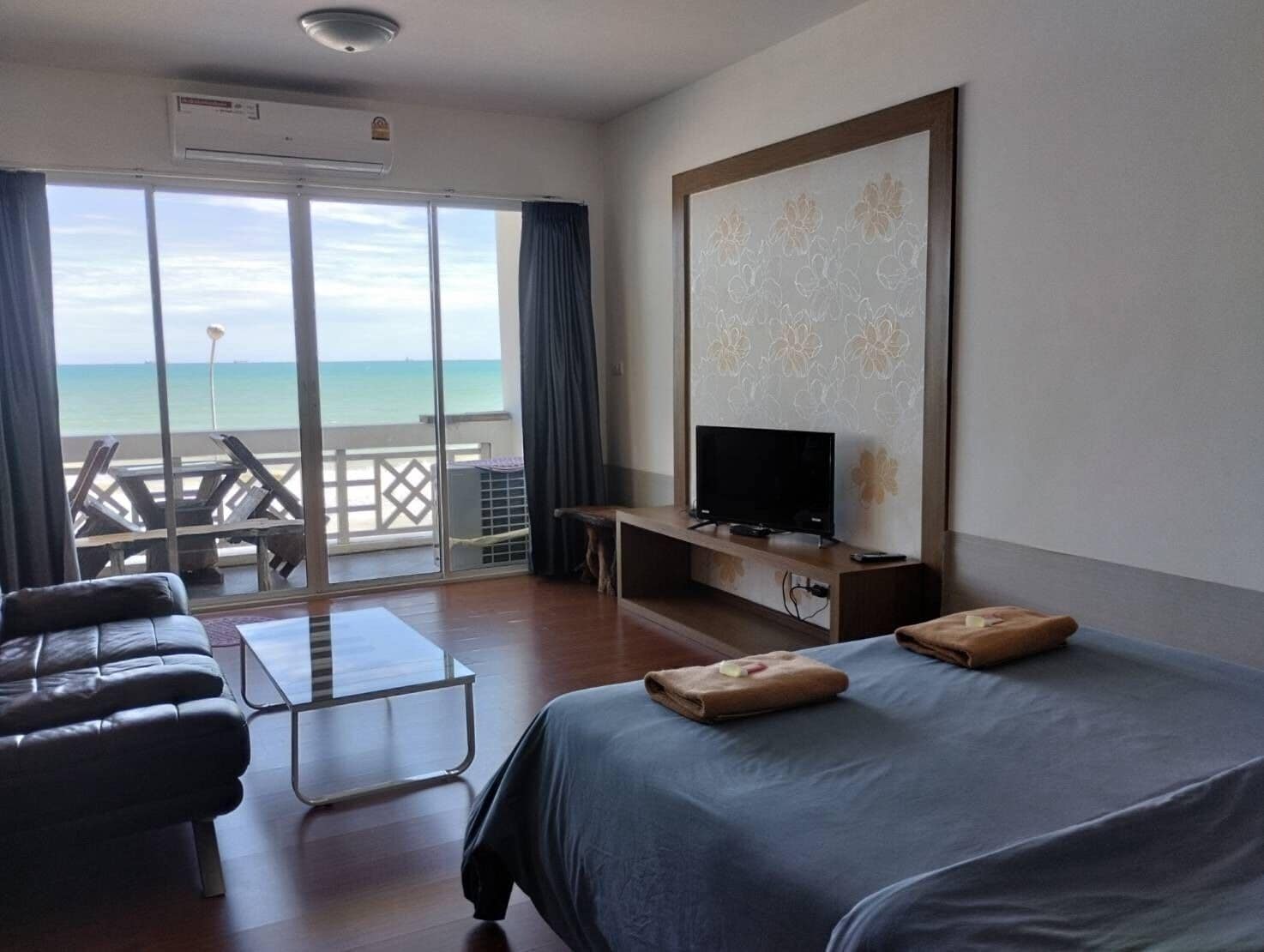 A hotel room with a bed, a TV, a desk, and a view of the ocean.