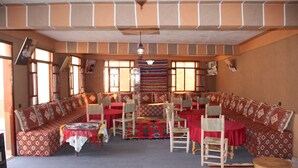 Una habitación con un sofá grande, varias sillas, una mesa de comedor y un tapete estampado.