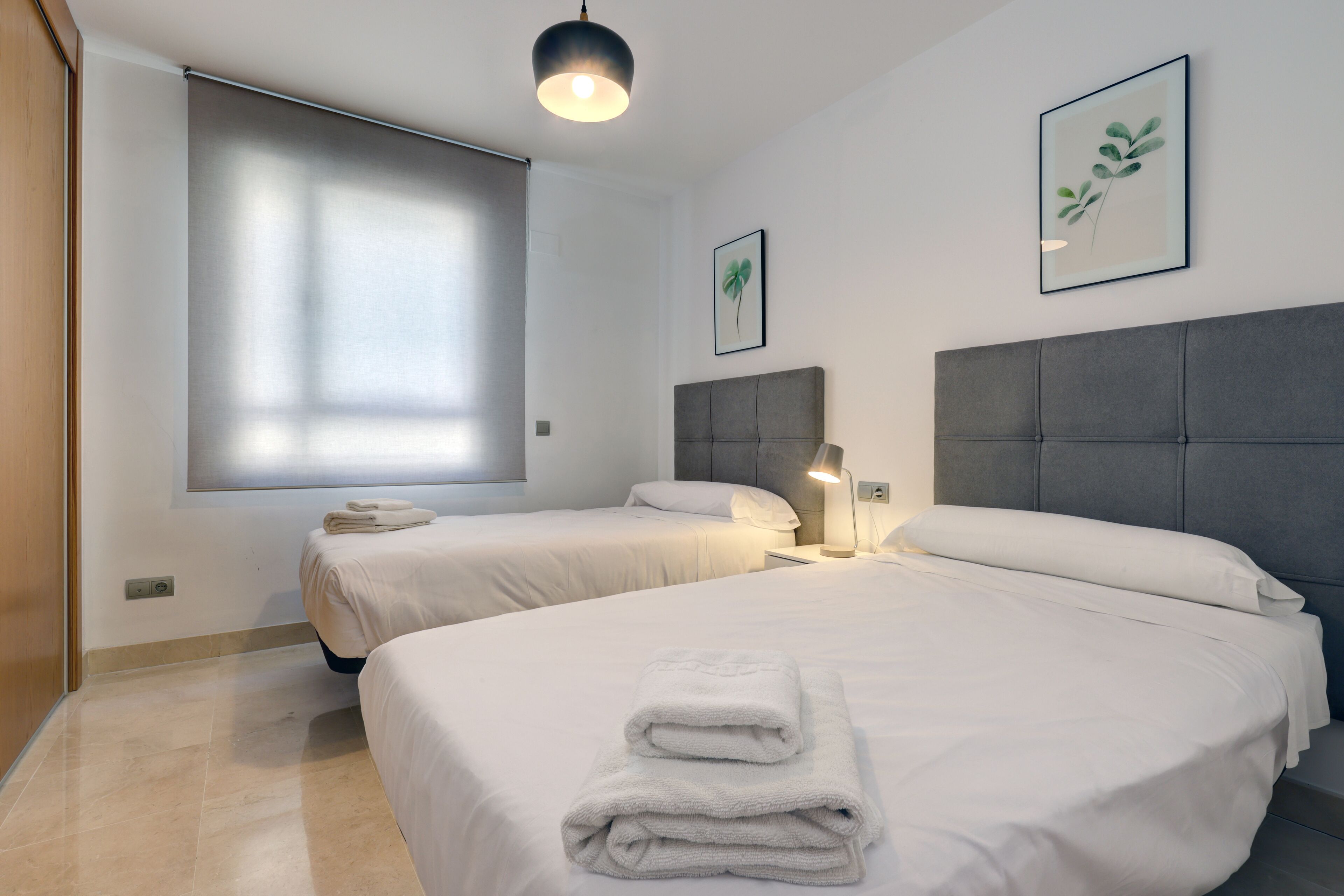Une chambre d’hôtel avec deux lits, une grande fenêtre et des œuvres d’art accrochées aux murs.