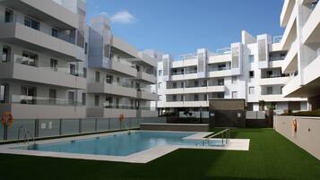 Una piscina al aire libre de temporada, sombrillas, tumbonas