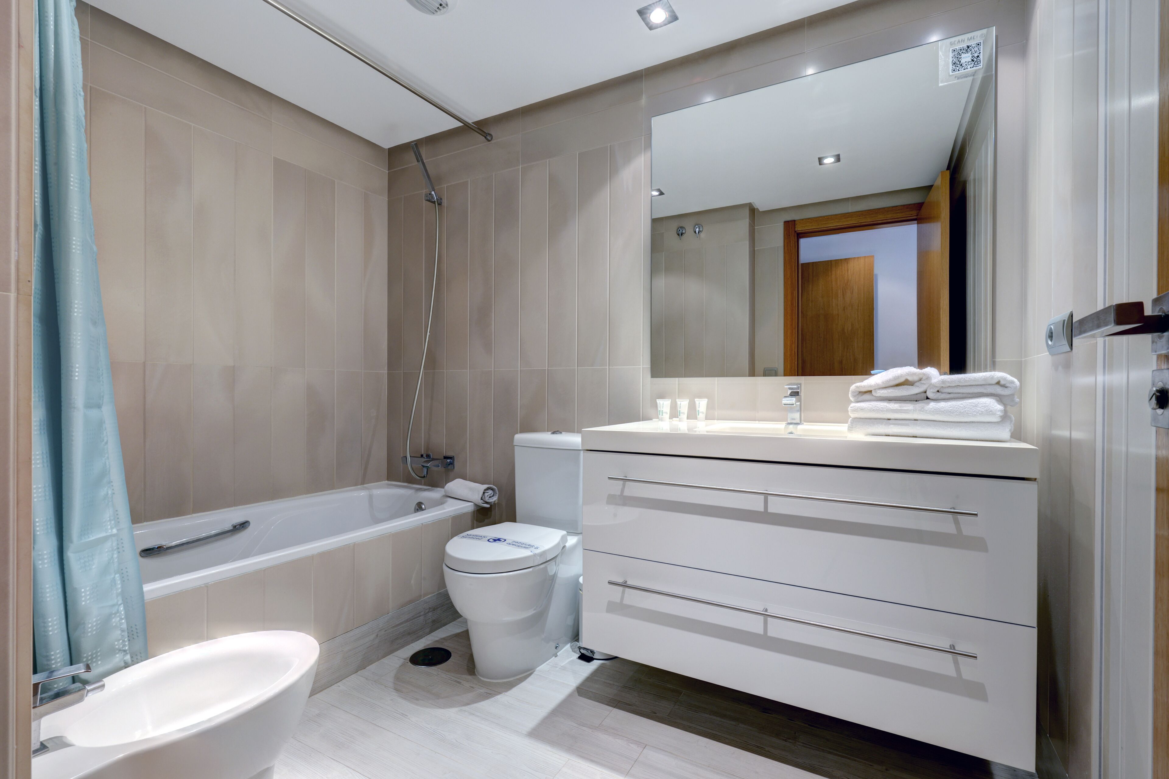 Un baño moderno con bañera, inodoro, lavamanos y tocador.