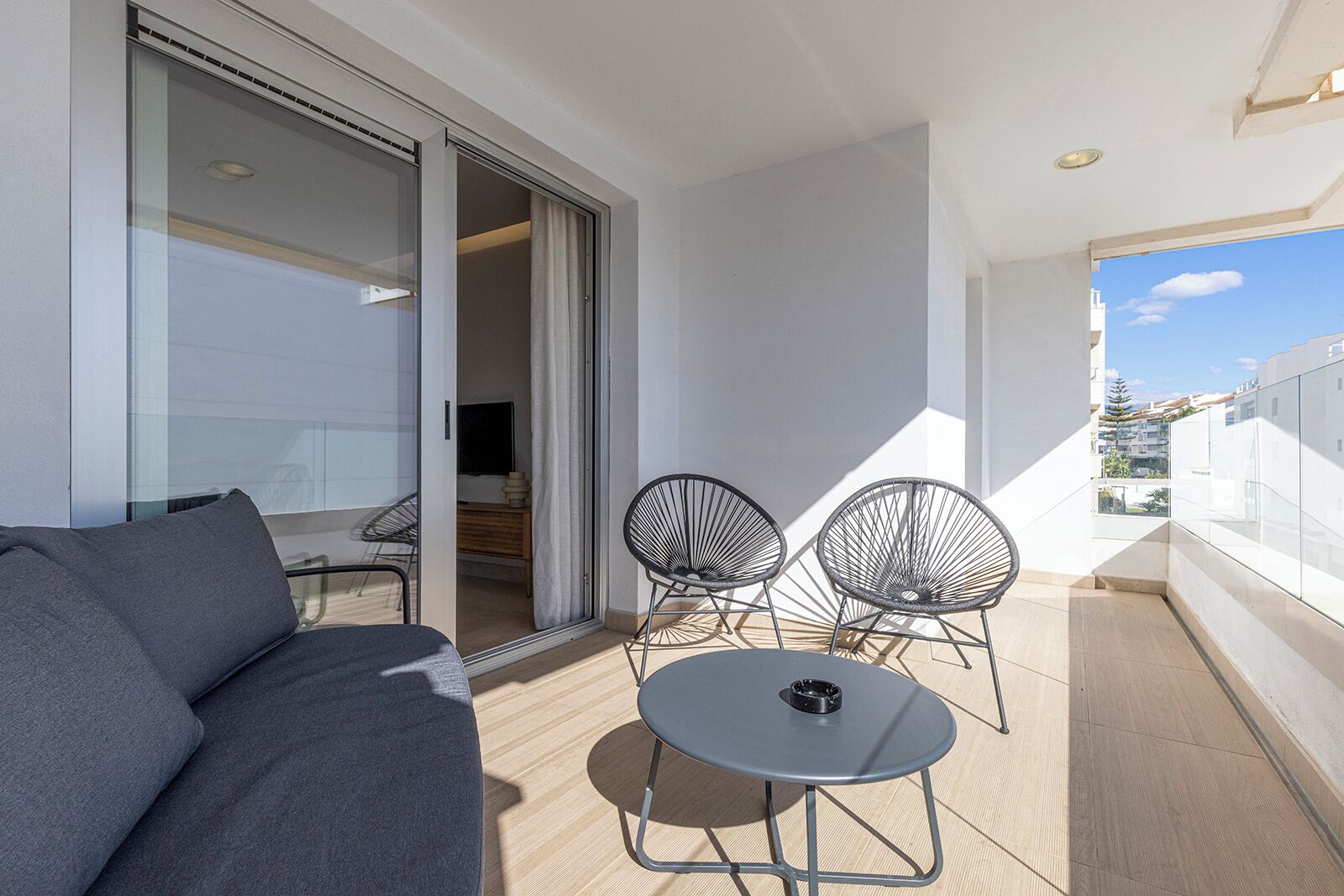 A balcony with a sofa, two chairs, and a small table.