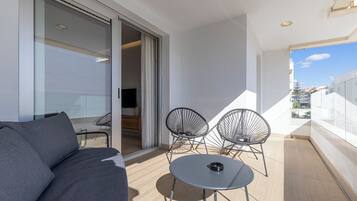 A balcony with a sofa, two chairs, and a small table.