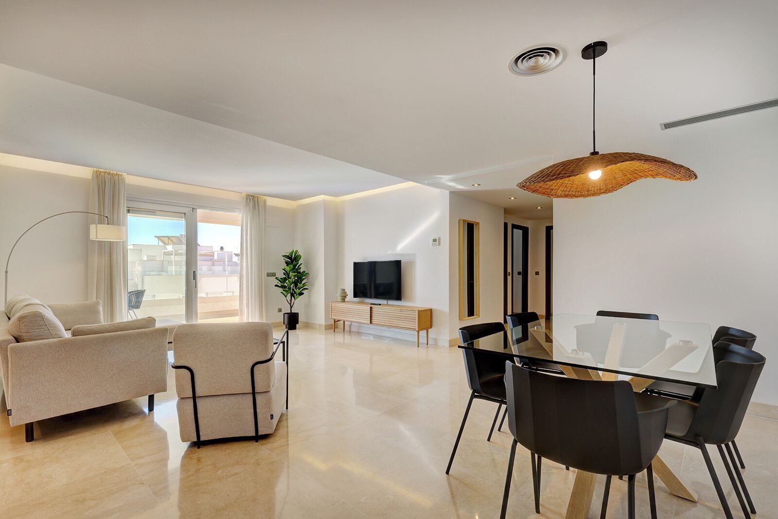 A modern living room with a sofa, chairs, a dining table, and a TV.