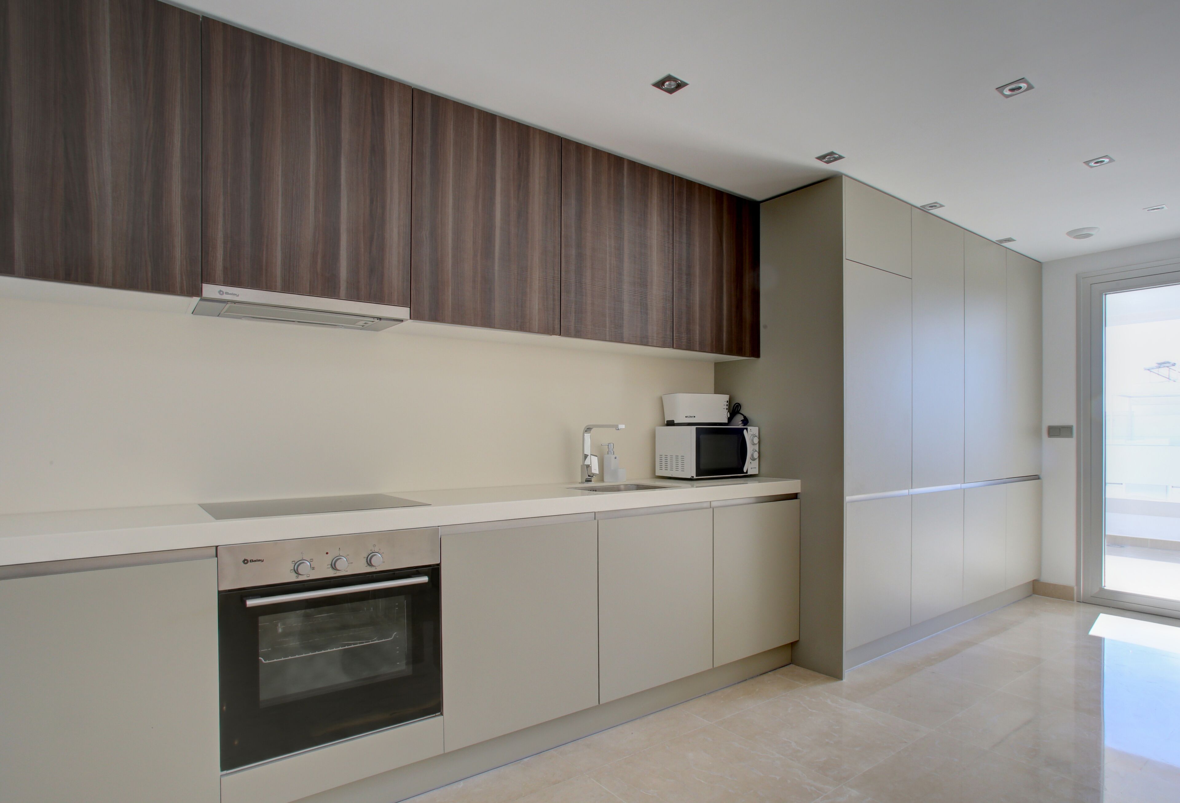 A modern kitchen with a built-in oven, microwave, and a sleek countertop.