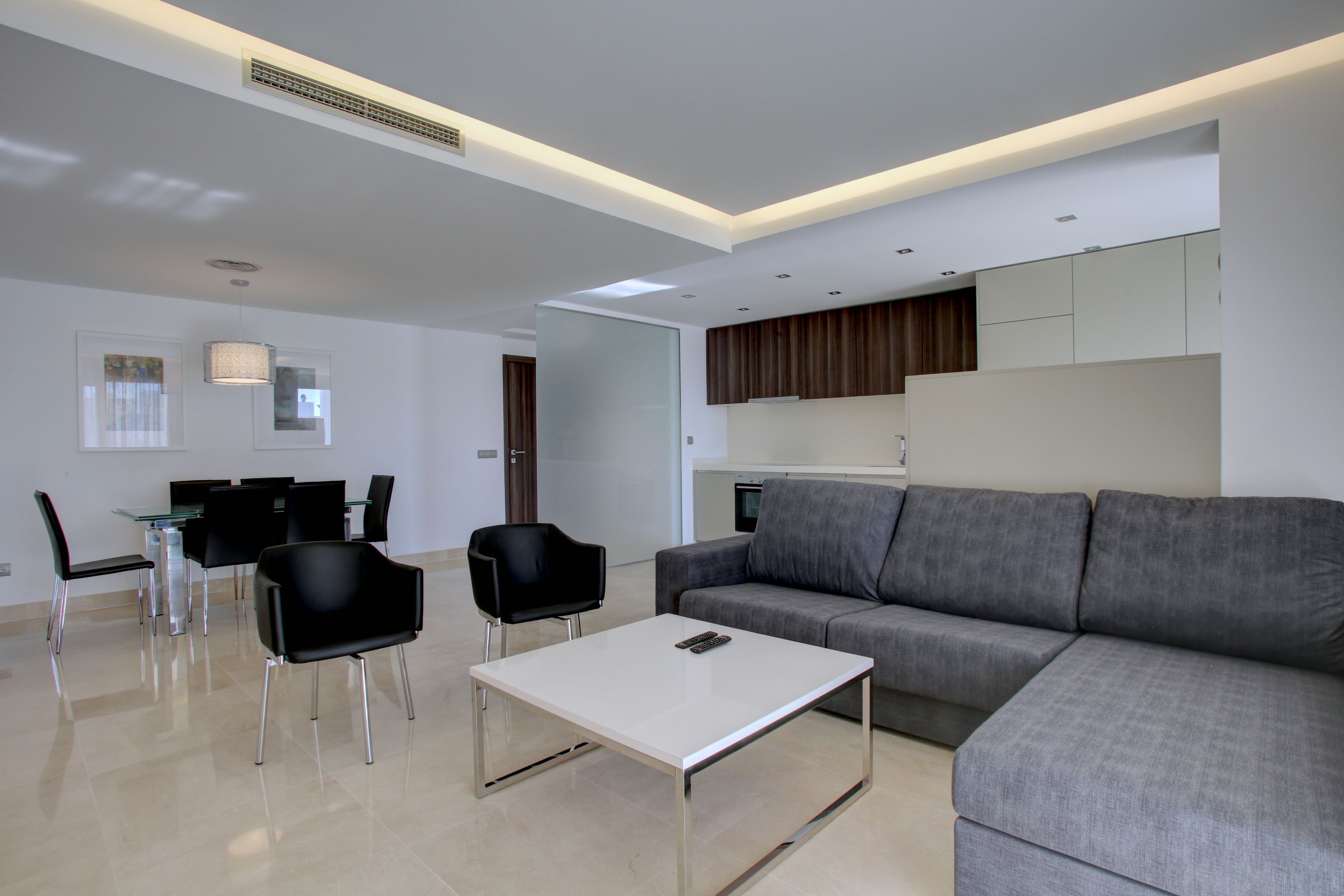 A modern living room with a grey sofa, a white coffee table, and black chairs.