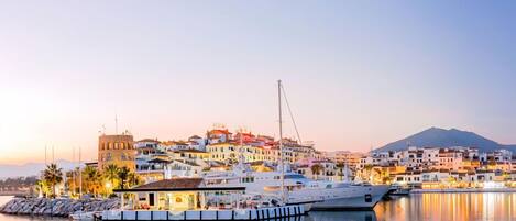 A marina with boats docked, a hotel, and a mountainous backdrop.