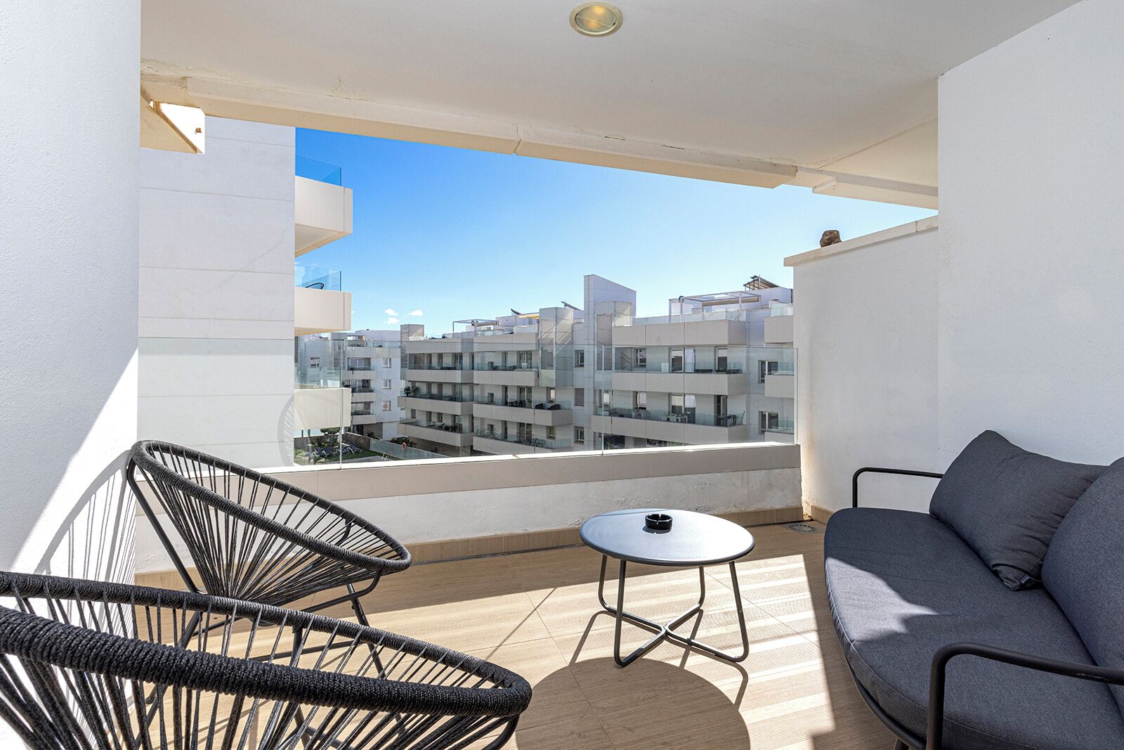 A balcony with a sofa, two chairs, and a small table.