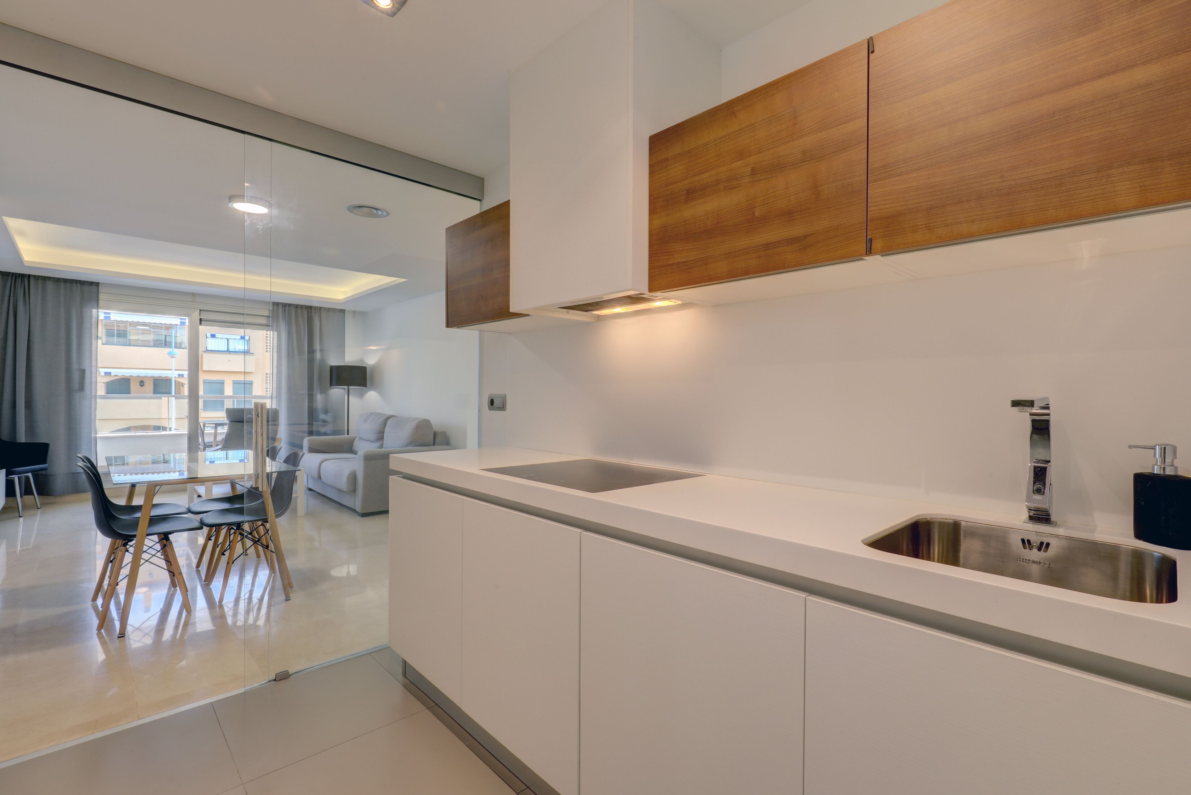 A modern kitchen with white cabinetry, a stainless steel sink, and wooden accents.