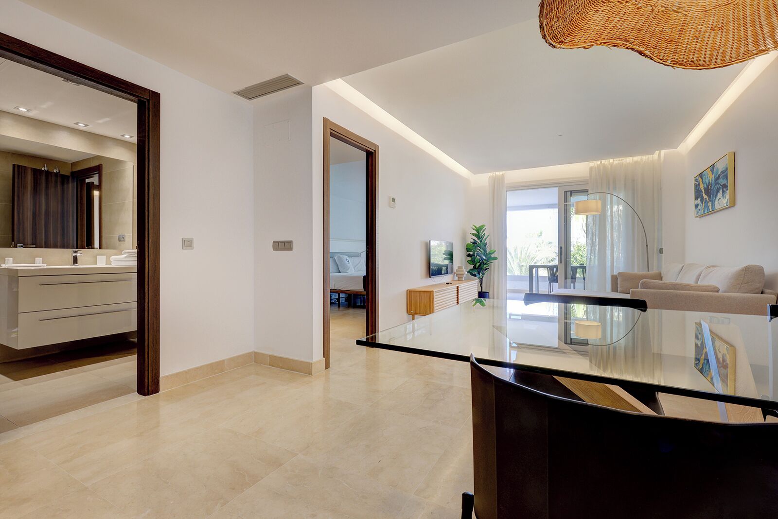 A modern living room with a glass coffee table, a sofa, and a dining area with a glass top table.