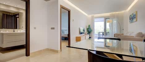 Una sala de estar moderna con una mesa de centro de vidrio, un sofá y una zona de comedor con una mesa de superficie de vidrio.