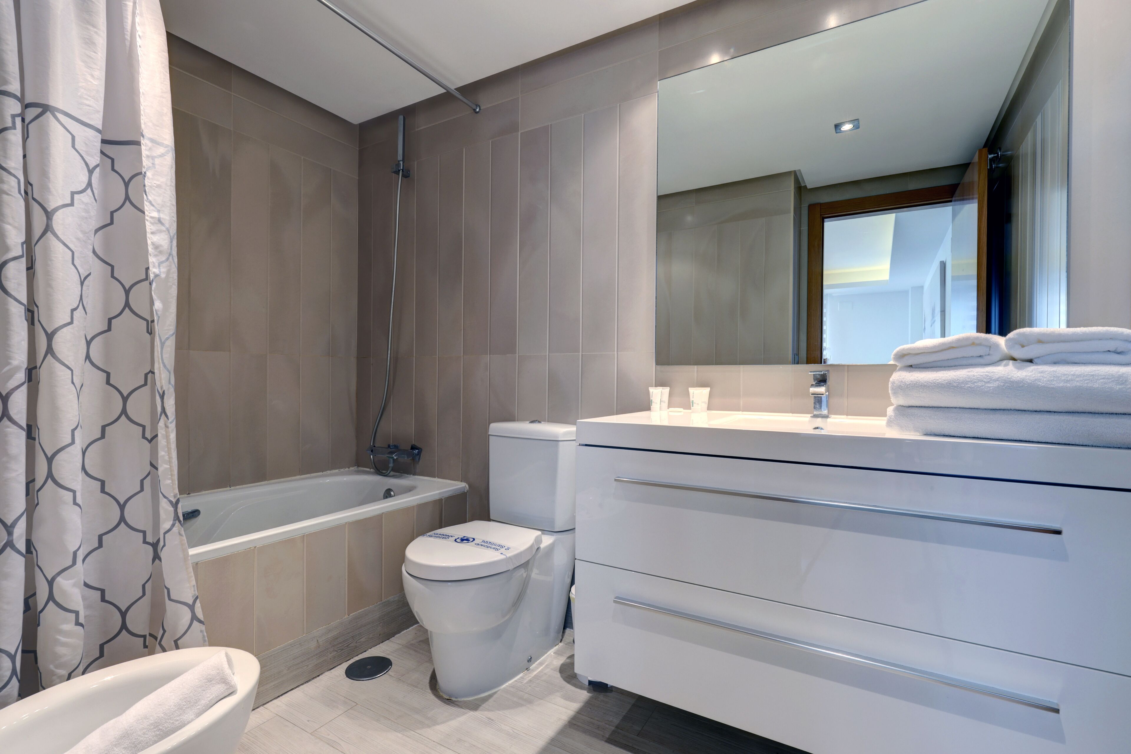 Un baño moderno con bañera, inodoro y tocador.