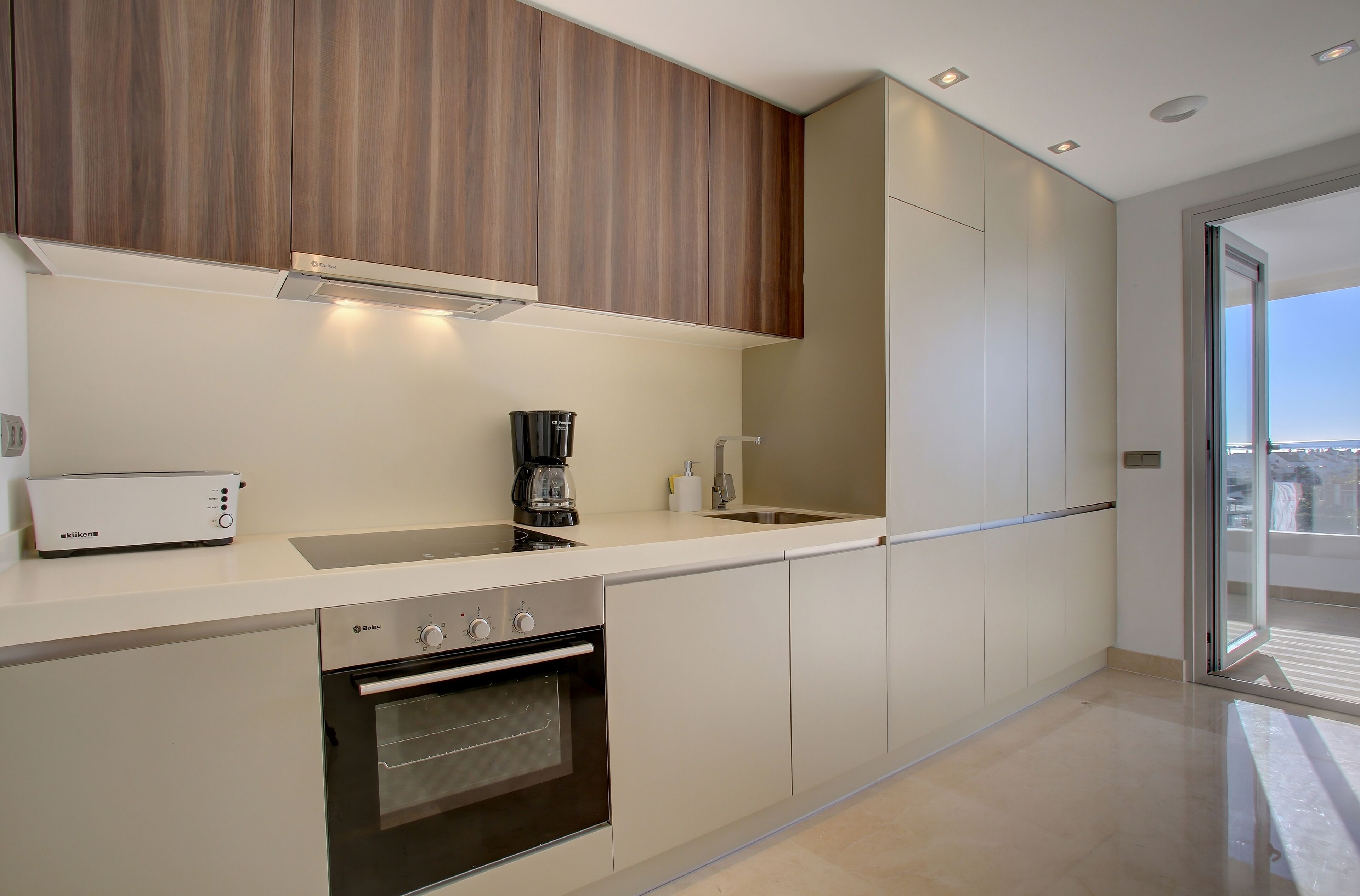 A modern kitchen with a built-in oven, a coffee maker, and a dishwasher.