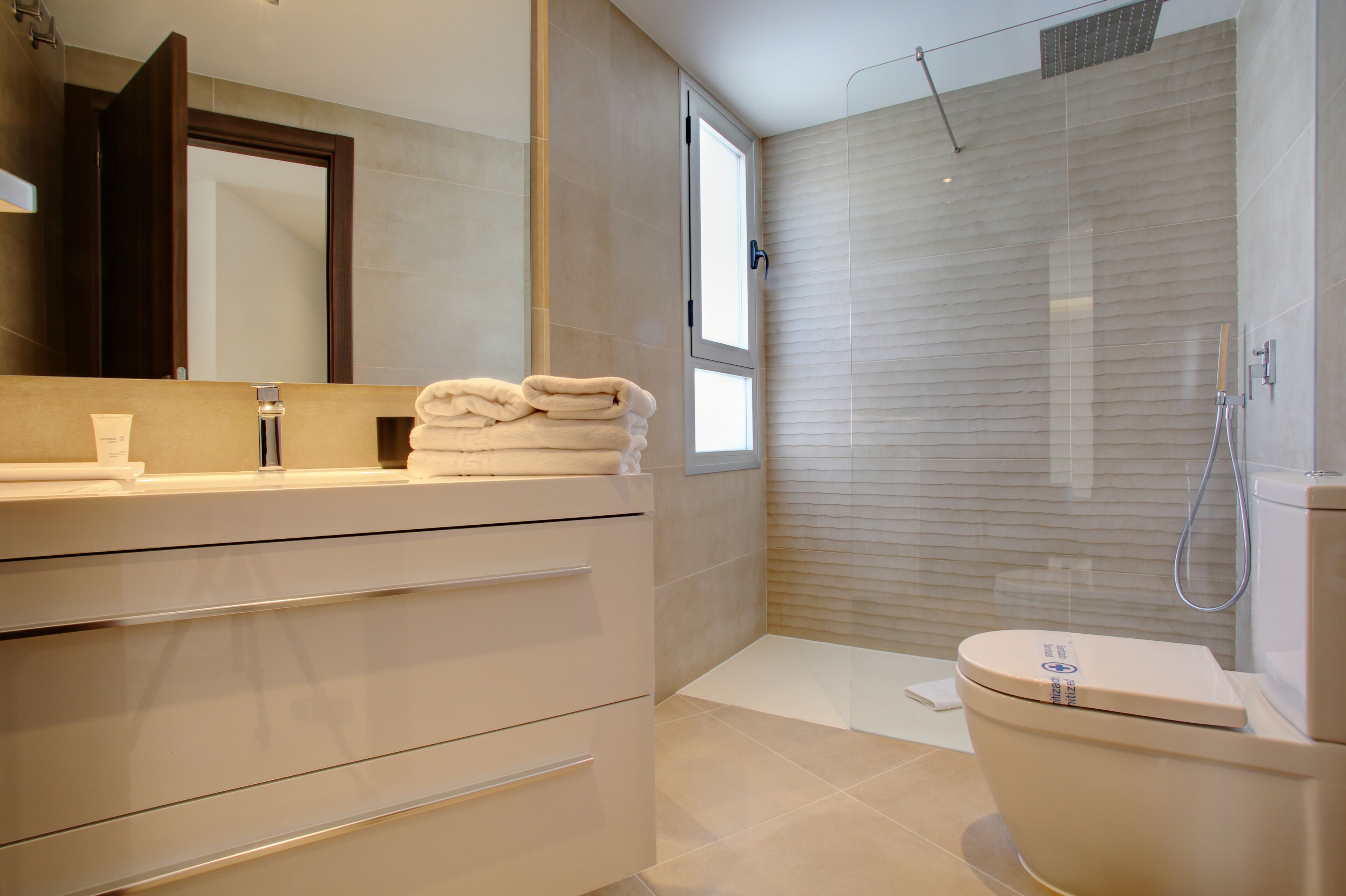 A modern bathroom with a large mirror, a toilet, and a shower area.