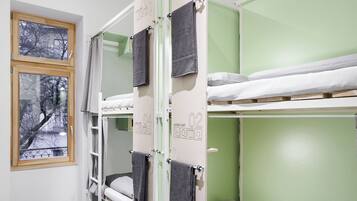 Un dormitorio con literas, una ventana con vistas a árboles y una puerta con una toalla colgada.