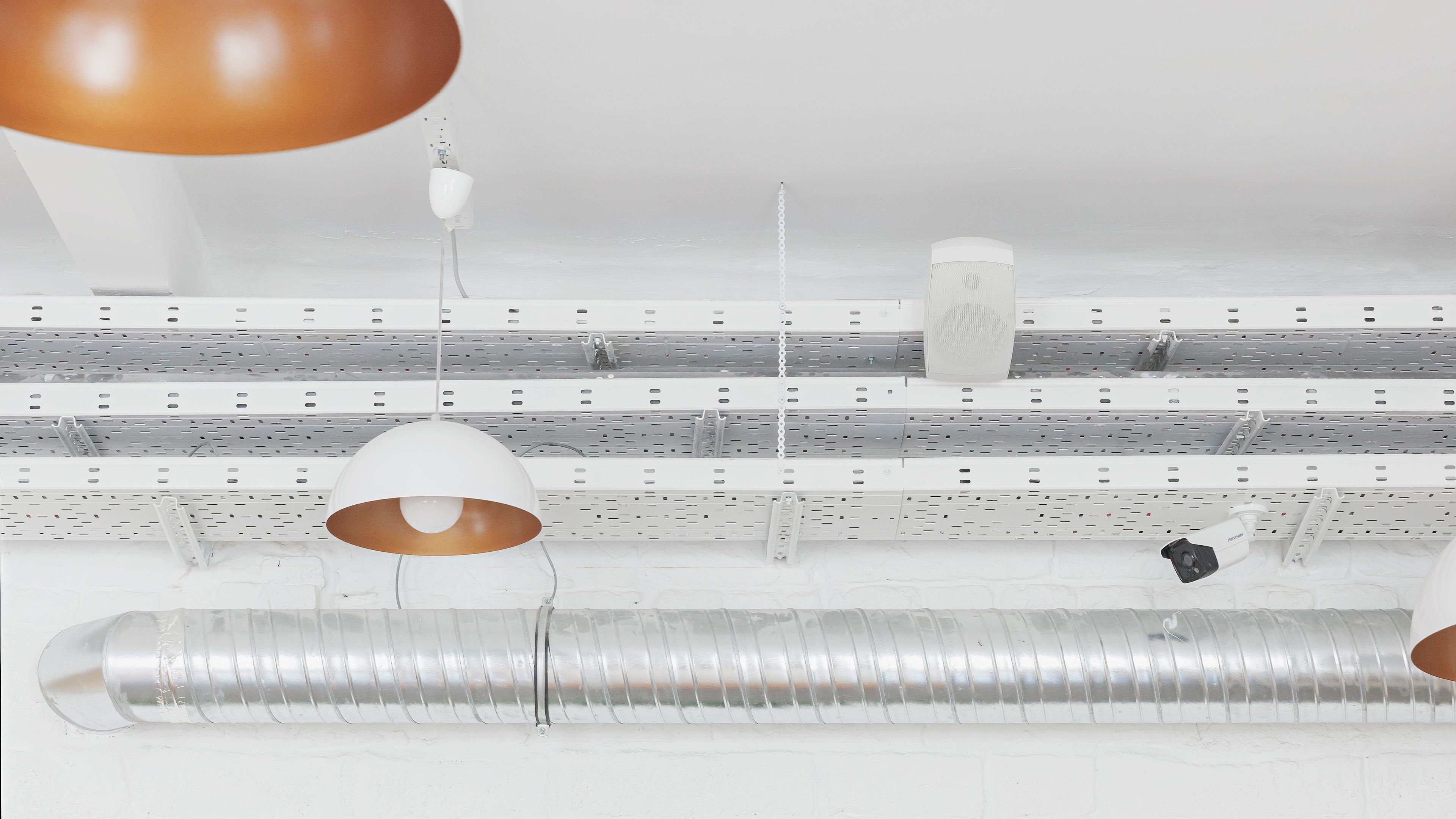 A ceiling with multiple light fixtures, air ducts, and a white ceiling fan.