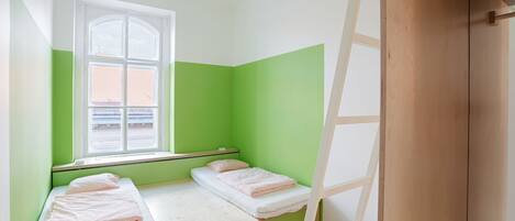A room with two beds, a window, and a wooden ladder.