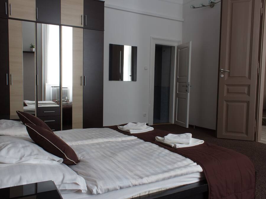 Un dormitorio con una cama grande, un armario, un espejo y una puerta que da a un baño.