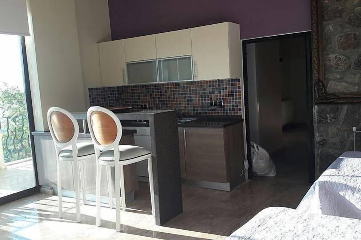 A compact kitchen with a tiled backsplash, a dining area with two chairs, and a view of the outdoors.