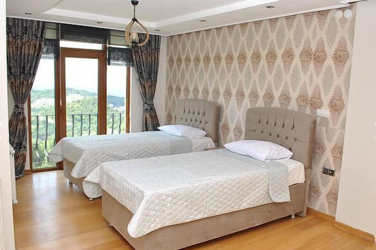 A bedroom with two beds, a balcony, and a patterned wallpaper.