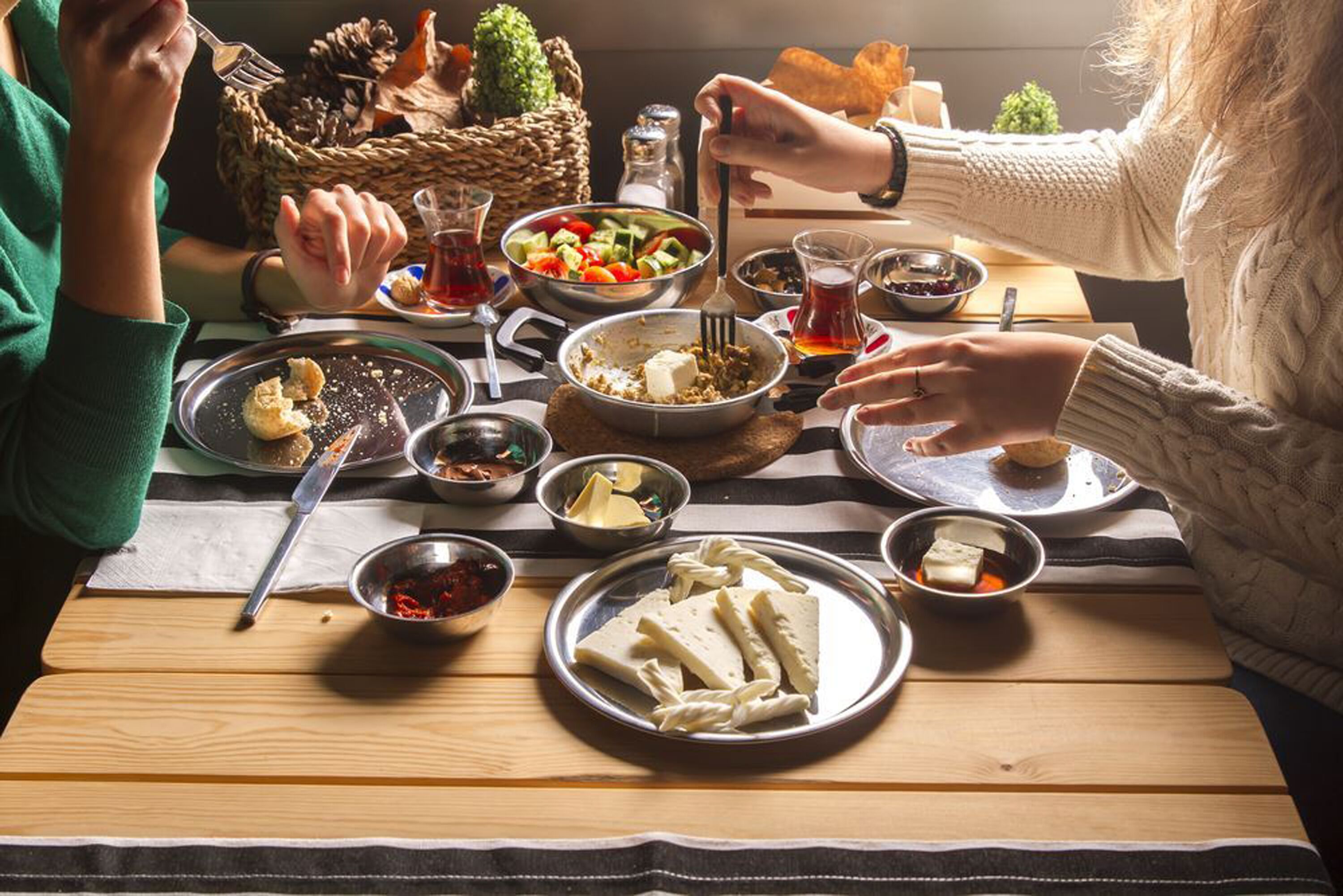 A dining table with various dishes, utensils, and condiments.