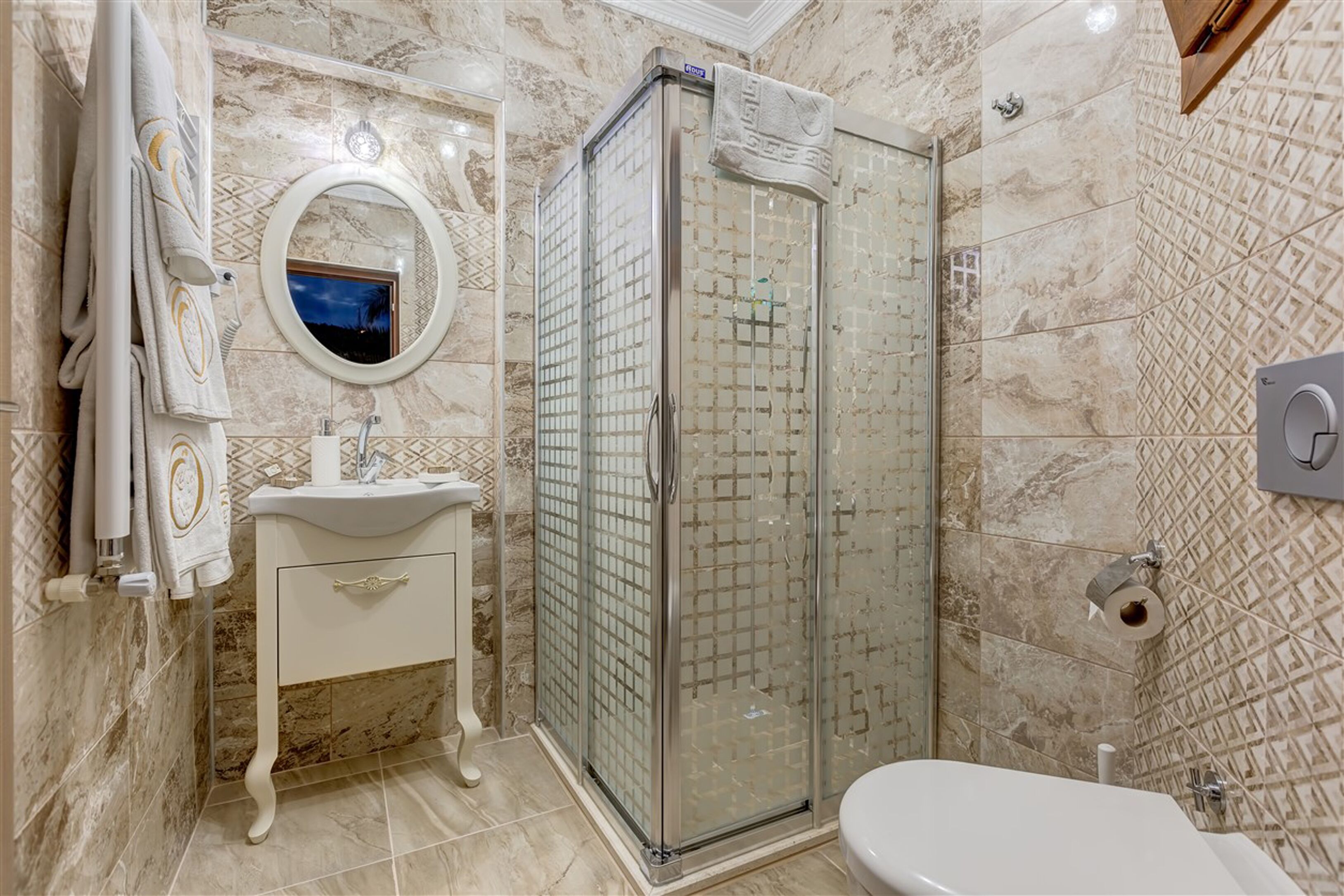 A bathroom with a glass-enclosed shower, a sink with a mirror, and a toilet.