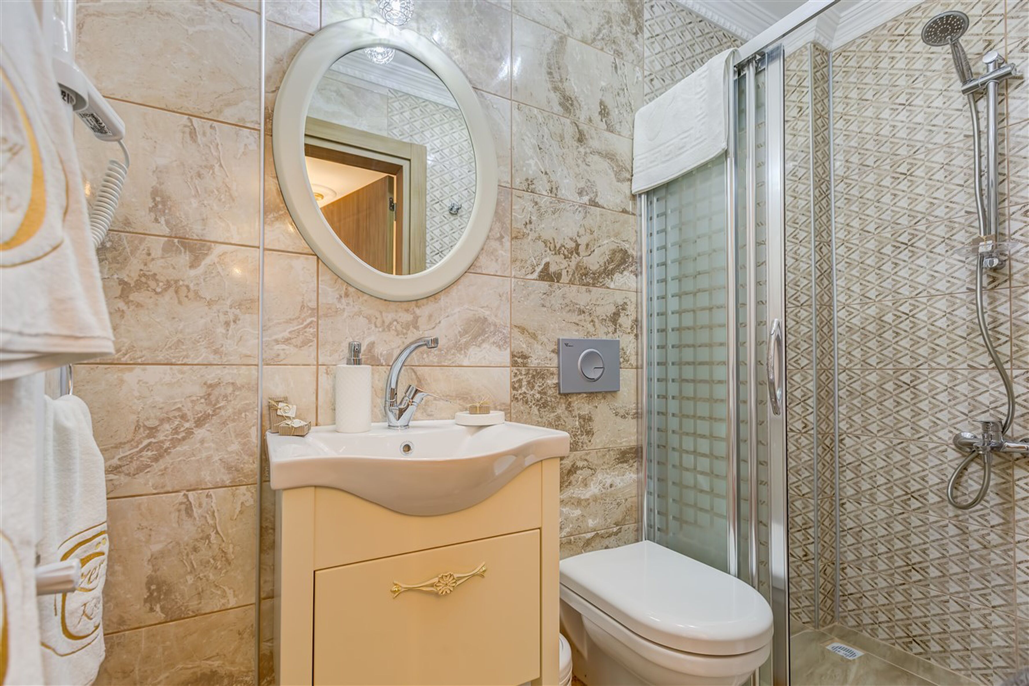 A bathroom with a marble sink, a toilet, and a glass-enclosed shower.