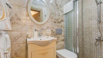 A bathroom with a marble sink, a toilet, and a glass-enclosed shower.