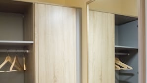 A wooden wardrobe with a mirror, a hanging rack, and a small box.