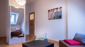 A modern living room with a large mirror, a sofa, a small table, and a painting on the wall.