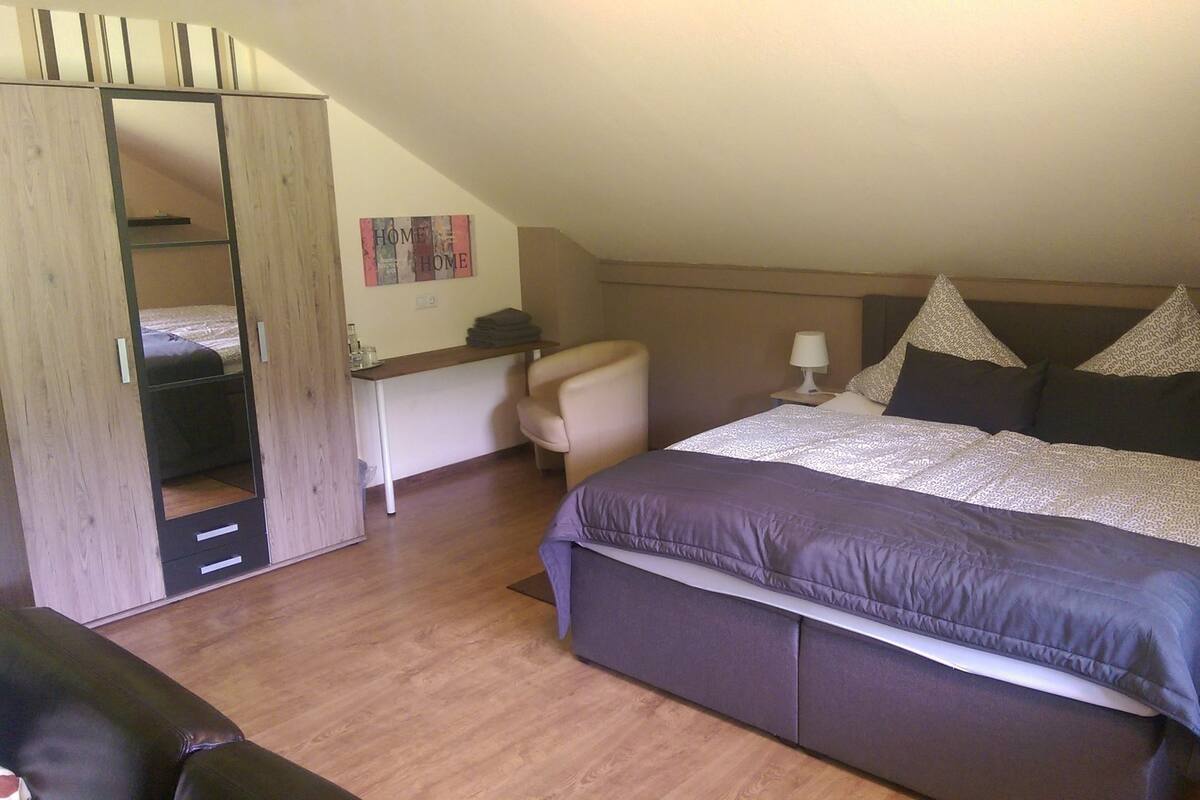 A bedroom with a bed, a desk, a chair, and a wardrobe.
