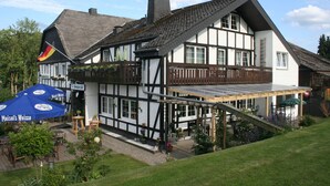 Un edificio tradicional de entramado de madera con un balcón, asientos al aire libre y un letrero que dice 'Maisel's Weiss'.