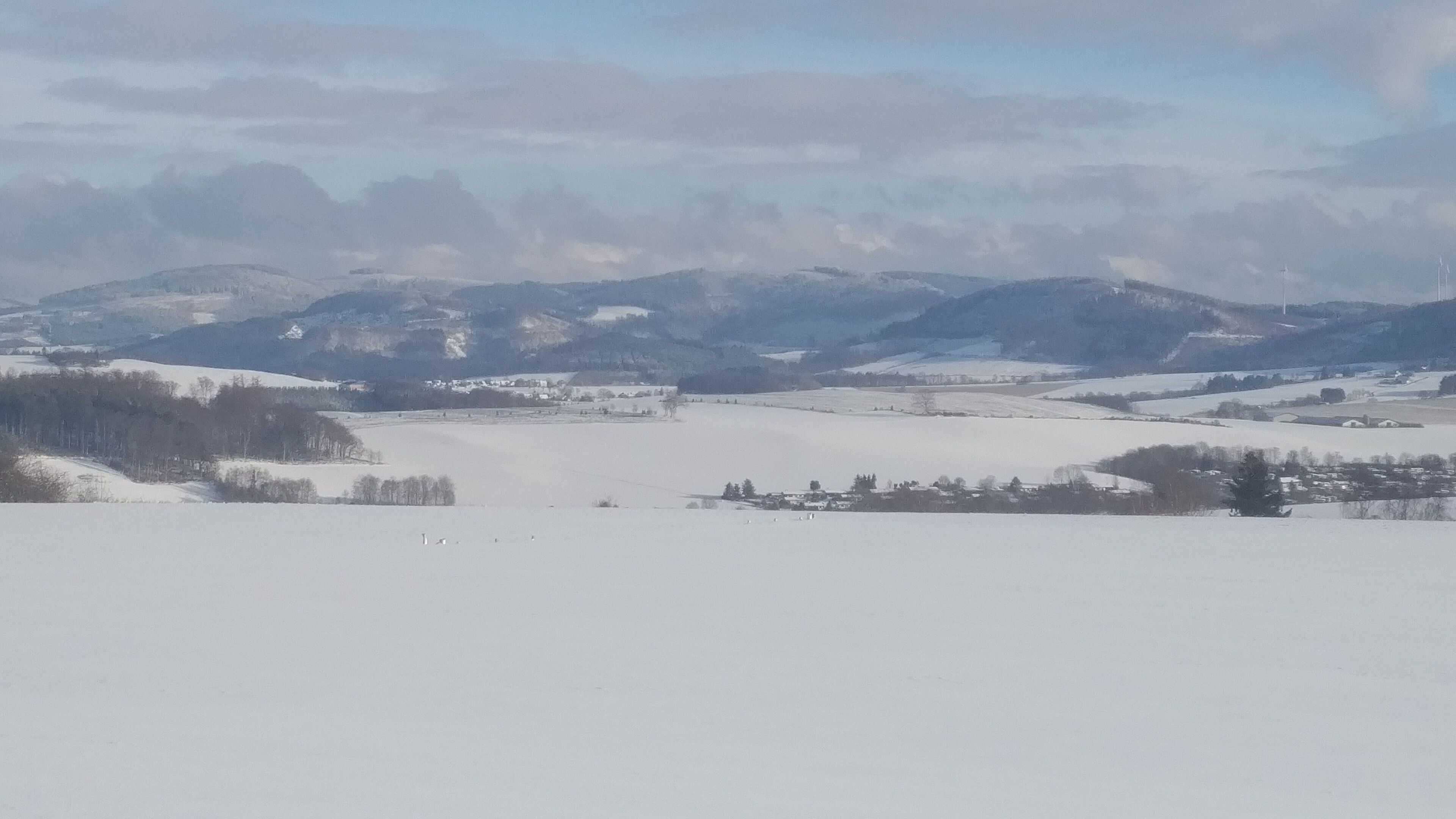 A snowy landscape with a village and mountains in the background.
